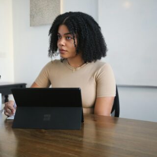 Female worker sitting in a board room with black Surface laptop on the table