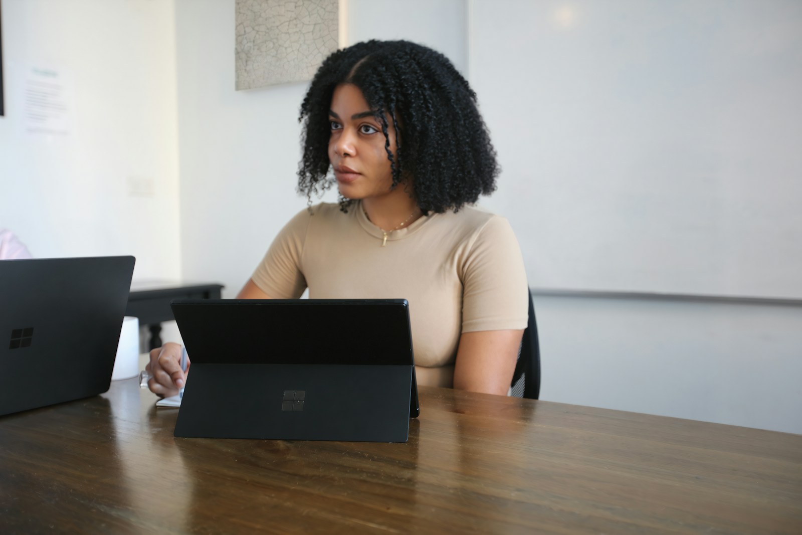 Female worker sitting in a board room with black Surface laptop on the table